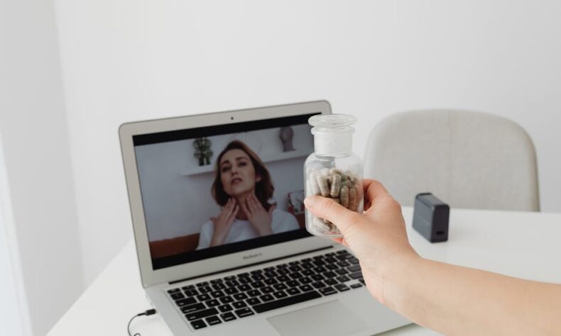 Person holding supplements during a virtual consultation with a doctor on a laptop. - Photo by www.kaboompics.com on Pexels