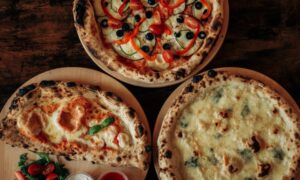 Top view of three assorted pizzas with various toppings on wooden boards. - Photo by Anhelina Vasylyk on Pexels
