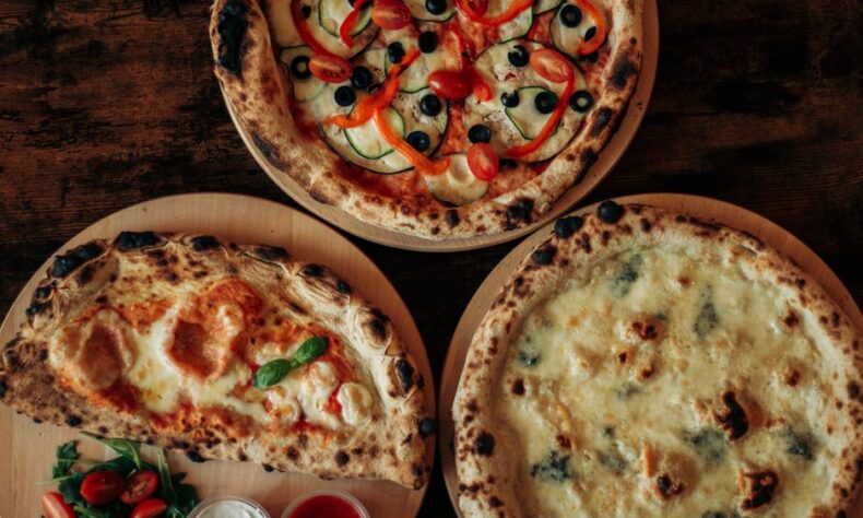 Top view of three assorted pizzas with various toppings on wooden boards. - Photo by Anhelina Vasylyk on Pexels