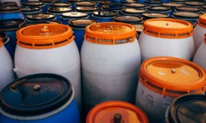 Close-up of blue and white plastic barrels with orange lids in storage area. - Photo by Markus Winkler on Pexels