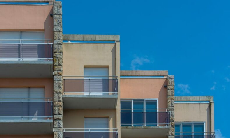 Modern apartment building with balconies against clear blue sky. Urban architecture scene. - Photo by Jan van der Wolf on Pexels